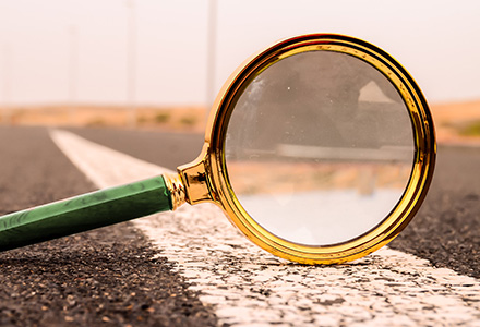 Magnifying glass balancing on a roadway